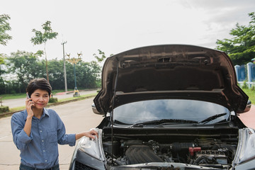 car is broken on the country road and Women talking on the phone ask for help .