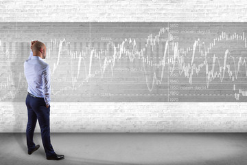 Man in front of a wall thinking about a stock exchange interface - tradex concept