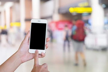 Hands woman are holding touch screen smart phone,tablet on Blurred Traveler at airport terminal for background.