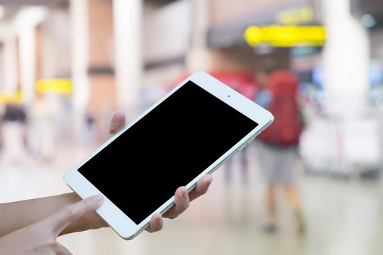 Hands woman are holding touch screen smart phone,tablet on Blurred Traveler at airport terminal for background.