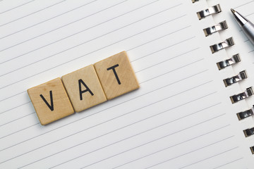 VAT text (Value Added Tax) on wood pieces isolated on white note pad