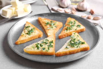 Tasty bread slices with garlic and herbs on tray