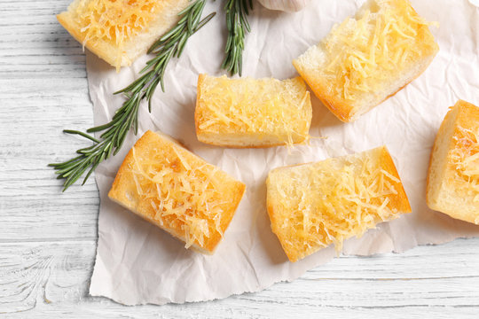 Tasty bread slices with garlic and cheese on paper