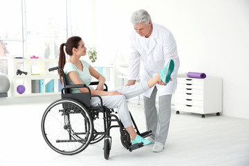 Young disabled woman with senior orthopedist in rehabilitation clinic