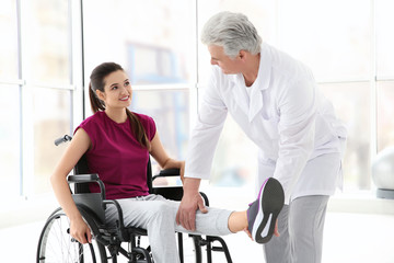 Fototapeta na wymiar Young disabled woman with senior orthopedist in rehabilitation clinic