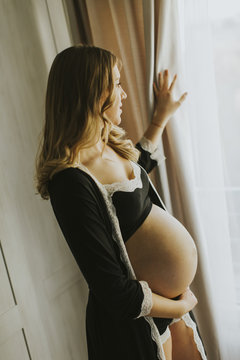 Pregnant woman wearing lingerie and posing in the room