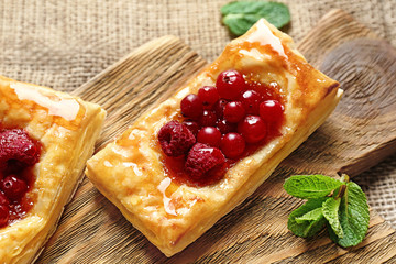 Tasty puff pastry dessert with berries and honey on wooden board