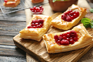 Delicious pastries with berries and honey on cutting board