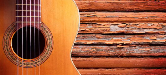 Naklejka premium Fondo de música.Detalle de guitarra española y pared de madera.