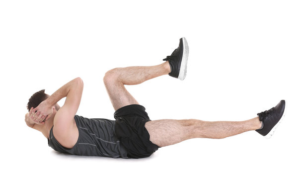 Young man doing bicycle crunch exercise on white background