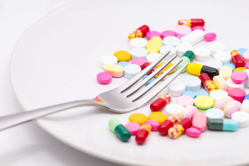 Pills on white plate with fork. Pill instead of food. diet