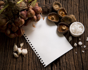 Fototapeta na wymiar Raw shiitake mushroom and notebook paper on wooden table.