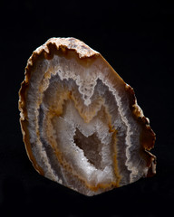 Partially polished multicolor agate geode with crystaline druzy center on black background