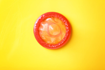 Red condom on color background. Safe sex concept
