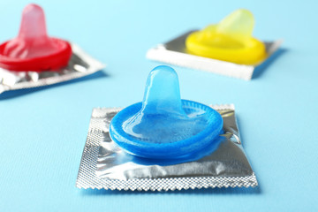 Open and wrapped condoms on color background. Safe sex concept