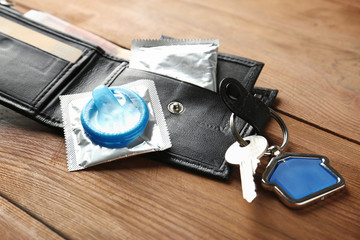 Wallet with key and condoms on wooden table. Safe sex concept