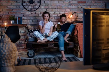 Naklejka na ściany i meble Young couple watching tv at home