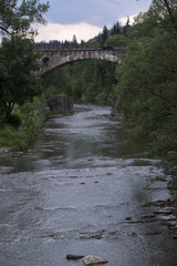 Fototapeta na wymiar Mountain river and stone bridge