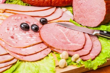 Meat and knife on the background of lettuce, cultivated mushrooms, olives in various angles