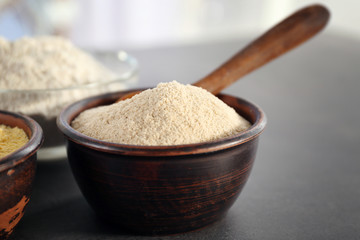 Wooden bowl with buckwheat flour on table