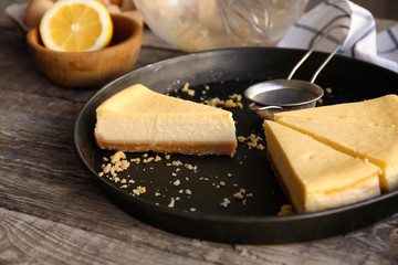 Tray with pieces of delicious cheese cake on kitchen table