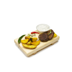 Grilled beef medallion with potato in a rustic wooden setting, high angle view isolated