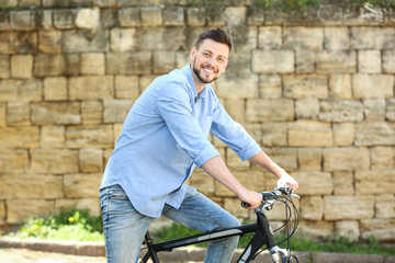 Handsome young man riding bicycle outdoors on sunny day