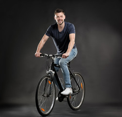 Fototapeta na wymiar Handsome young man riding bicycle on dark background
