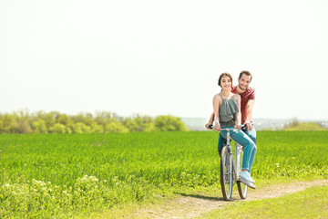 Happy young couple riding bicycle in countryside