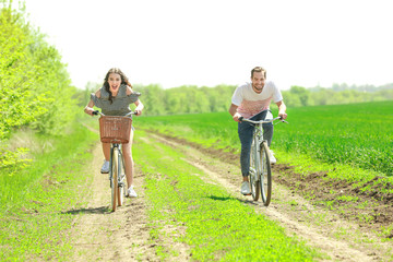 Happy young couple riding bicycles in countryside