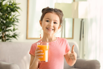 Cute little girl with glass of juice at home