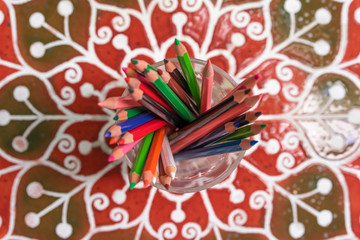 Color pencils in glass on a table, top view, closeup