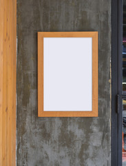 Blank poster in frame on gray concrete wall background, outdoor cafe 