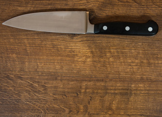 kitchen chef knife on the brown wooden table background. rustic kitchen table with copy space. top view.