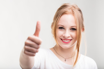 Smiling young woman giving a thumbs up