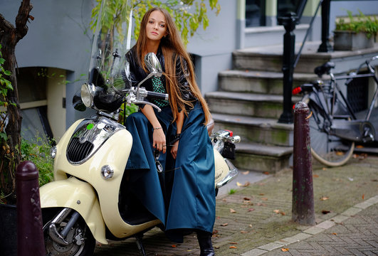 Portrait of a girl, model near motobike in the city street. Fashion, style, beauty.