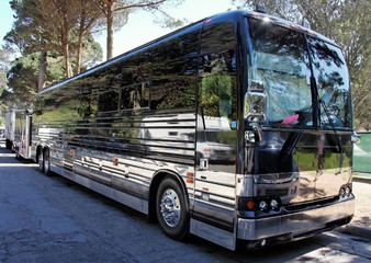 Parked black tour / charter bus in shaded area..