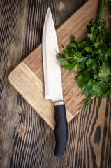 fresh dill and parsley on a cutting board with knife on wooden table