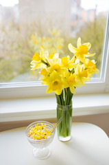 Posy of bright yellow daffodils on white wooden table
