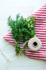 Green parsley and dill leaves on natural linen napkin on wooden background