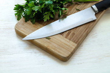 Fresh organic parsley with knife on wooden cutting board.
