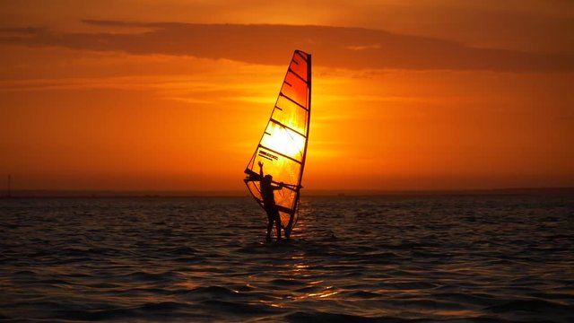Windsurfing near big sun at sunrise