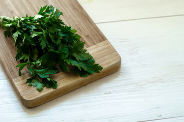 Parsley and dill on a cutting board, wooden background