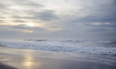 Black sand beach on the sunrise with white Indian ocean. Nobody in the beach. Paradise