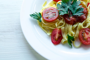 Tagliatelle pasta with tomato sauce decorated with basil leafs