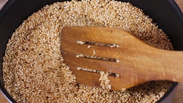 In a bowl, stir sesame with a spoon made of wood. Fashionable background from a tree. Sesame eastern spice or seasoning. Healthy lifestyle HD