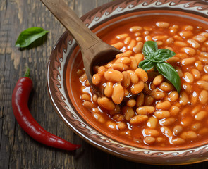 Beans in tomato in a dish on a wooden background