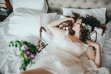 A beautiful stylish bride lies on the bed