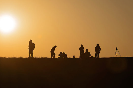 Silhouettes of hikers with backpacks enjoying sunset view