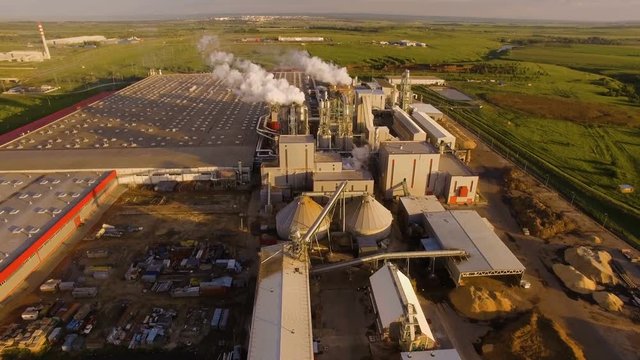 a huge concrete plant with pipes among the fields. aerial view